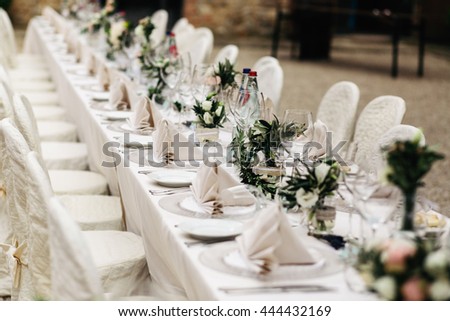 Dinner table decorated with olive branches and pink roses served for a wedding