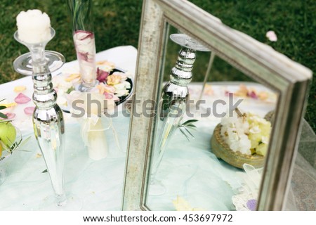 Silver candleholder stands behind an old mirror on the table