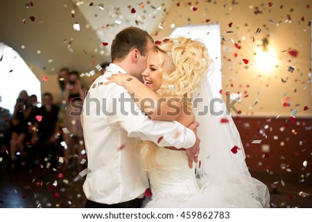 Red and white confetti falls around dancing wedding couple