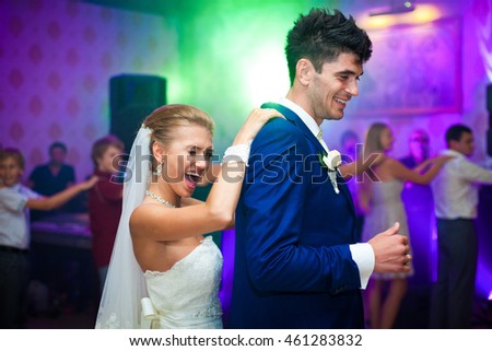 Bride smiles while dancing with a groom holding his back from behind