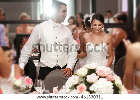 Happy handsome groom and beautiful smiling bride with guests at reception
