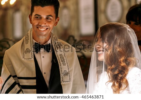 Jewish wedding. Beautiful bride looks at a groom
