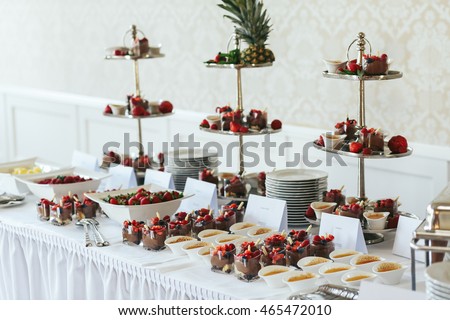 Red fruits and chocolate desserts stand on the white buffet