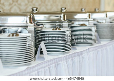 Heaps of white plates stand on the white buffet