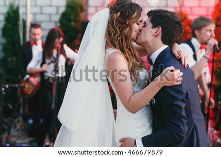 Groom holds bride with passion dancing before an orchestra