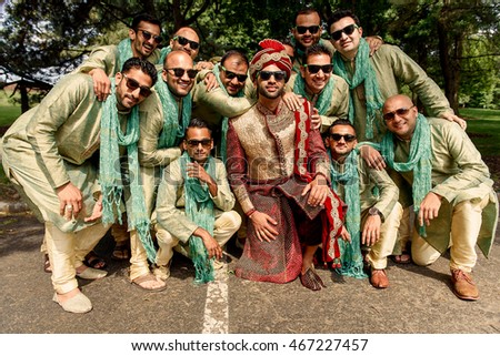 Funny groomsmen and  Indian groom in red suit pose outside