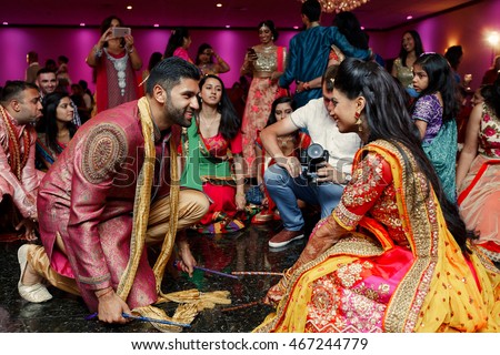 Indian wedding couple dressed in red suits beats on the floor with sticks during a dance