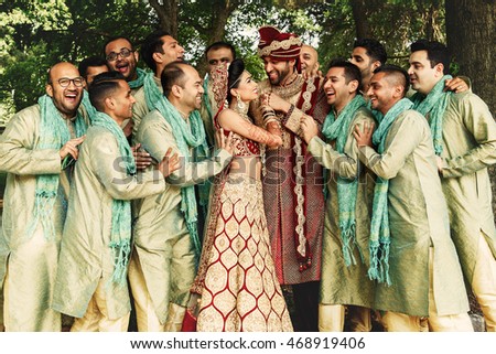 Groomsmen surround Indian wedding couple dressed in red suits