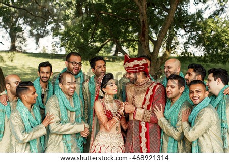 Groomsmen lean to an attractive Indian wedding couple while posing in the garden