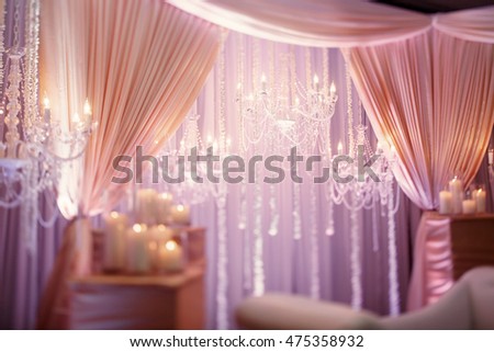 Luxury design. Restaurant hall decorated with pink curtains and bright chandeliers over them