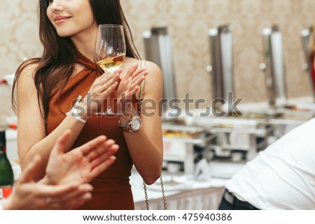 Elegant woman in brown dress applauds holding a glass of wine in her arms