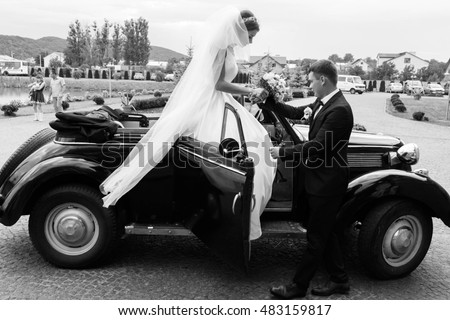 groom helps the beautiful bride to leave the car