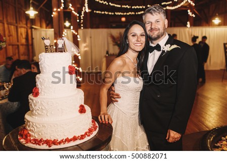Bride lies her hand over the wooden tray with white wedding cake