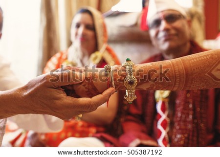 Closeup of Indian bride\'s hand wearing golden bracelets and held by a man