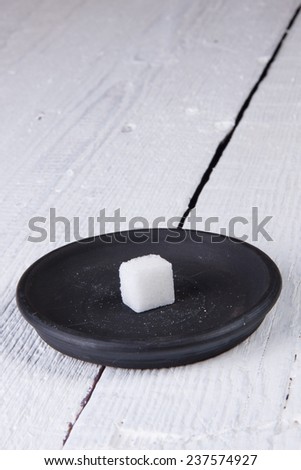 Square piece of refined sugar on a black saucer