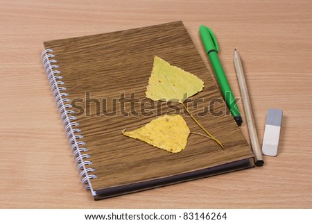 School notebook and pencil, pen, eraser, leaves