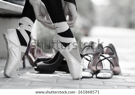 Closeup of a ballerina\'s feet in Point on the street, different kind of shoes in background