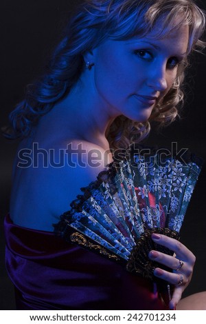 Portrait of young beautiful woman with fan in studio