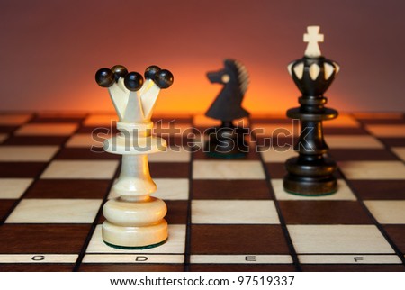Chess (queen, king and a horse) on a chess board. An art dark background.