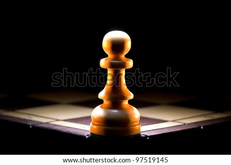 The struck pawn on a chess board. A dark art background.