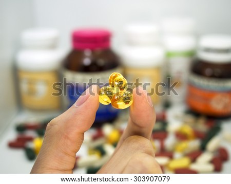 taking a fish oil tablet,Pills or vitamin in Medicine bottles with pill box,Vitamin, drug,multivitamin, herbal supplement capsules, Colorful,pills and tablets, background