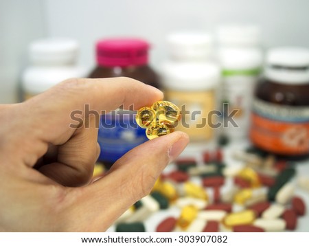 taking a fish oil tablet,Pills or vitamin in Medicine bottles with pill box,Vitamin, drug,multivitamin, herbal supplement capsules, Colorful,pills and tablets, background