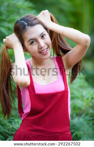 Cosplay style, portrait of a lovely girl with 2 pony tails hairstyle in red long leg suit behind green bamboo leaves background