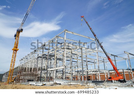 Structure of steel roof frame installation by mobile crane under the building in construction with blue sky