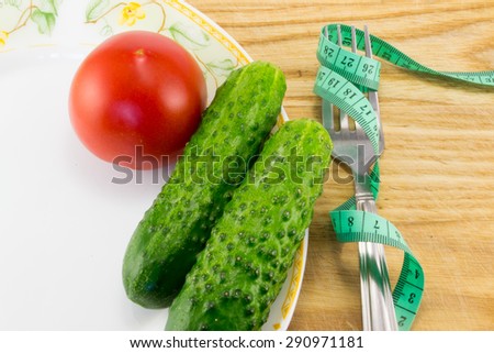Measuring tape and a fork with tomato isolated on background, concept of healthy food and diet