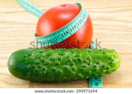 Cucumber and tomato with measuring tape over desk  - the concept of dieting and health