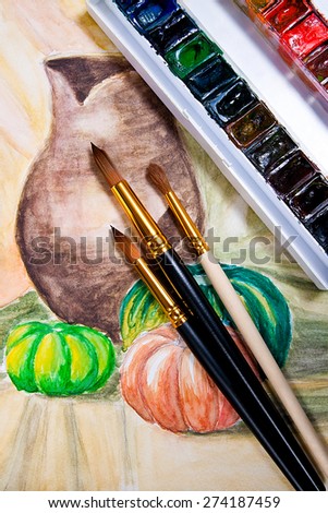 Paints and brushes on the watercolors painting of still life on the background.