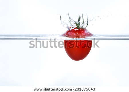 Cherry tomato falling into water with a splash