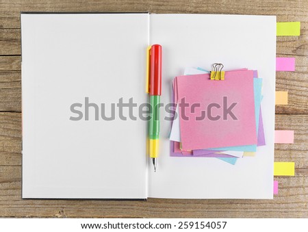 Colored stickers around notebook on old wooden table