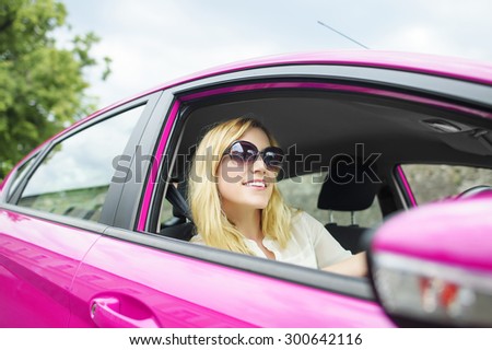 Happy attractive woman driving a new pink car.