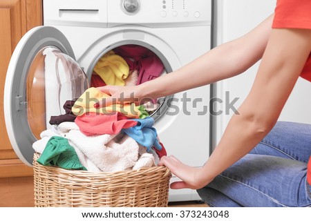 Preparing the wash cycle. Washing machine, hands and clothes.