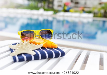 Sunglasses and the things on a poolside lounger.