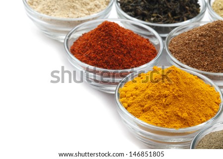 Variety of raw Authentic Indian Spices Powder on glass bowl isolated on white background in full-frame.
