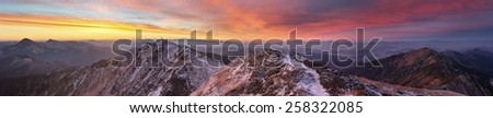 panorama of mountains covered with light snow. all lit yellow light of the sun. the sky beautiful red clouds