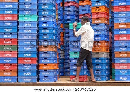 BANGALORE, INDIA - AUGUST 11, 2014: A man carrying colorful milk boxes in a dairy in Bangalore, India.