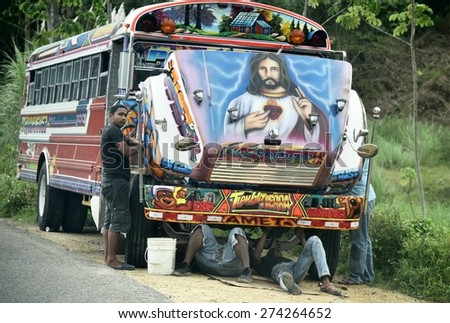 NEAR COLON, PANAMA - APRIL 20, 2015: Young men repairing a so called Diablo Rojo or Red Devil Bus which is colorfully painted with a picture of Jesus.