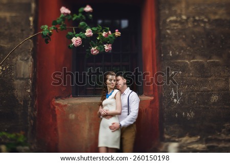 couple walk in old town lvov,huseband and his wife near the red wall and flowers