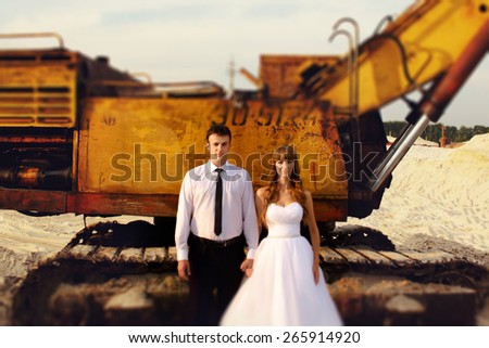fun portrait of the bride and groom on the beach near tractor