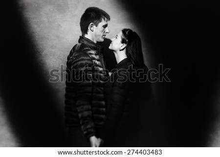 loving couple standing on a background of orange wall and their shadow of tree falls on the wall