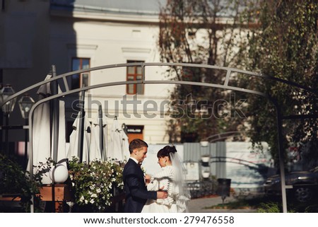wonderful rich bride and groom look at each other holding hands on the terrace