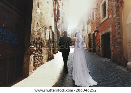romantic gentle luxury brunette bride and groom walking the streets of of tivoli italy
