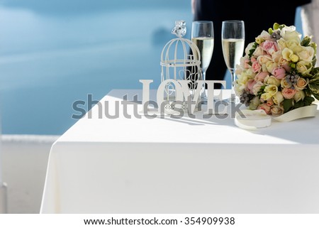 Closeup of table at wedding ceremony tent with flowers and white cage