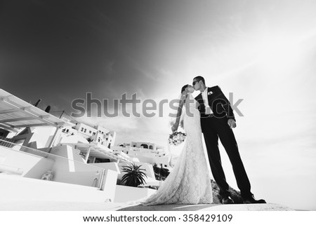 Romantic beautiful couple kissing on terrace with sea, islands and mountains in background b&w