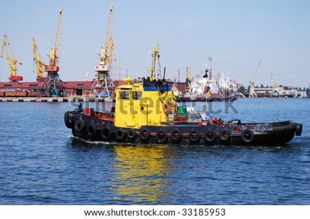 Small yellow towboat against the busy industrial port