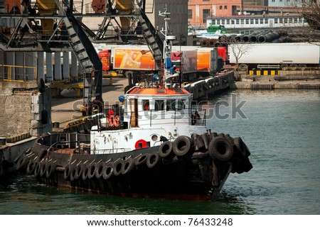 Tug boat in the port and cranes in the background