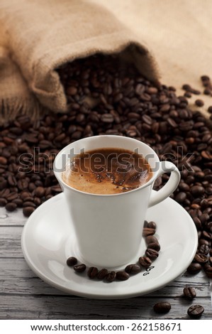 Fragrant, natural coffee in a cup standing on a wooden table in the coffee beans